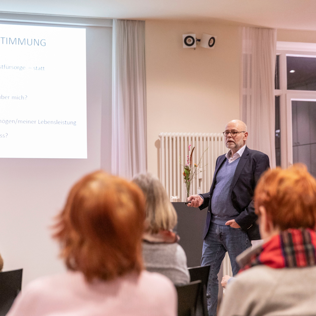 Rechtsanwalt Klaus Jakobsmeyer steht im Hamburg Leuchtfeuer Lotsenhaus vor eine Gruppe von Menschen und hält einen Vortrag.